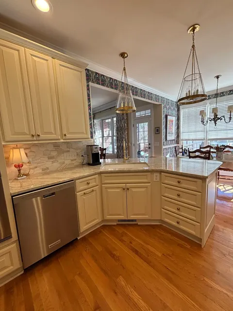Cream kitchen with curved island, pale marble countertop and pendant lights