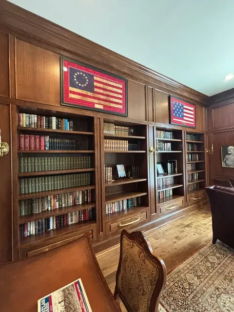 Walnut library with glass-front display cabinets and brass hardware