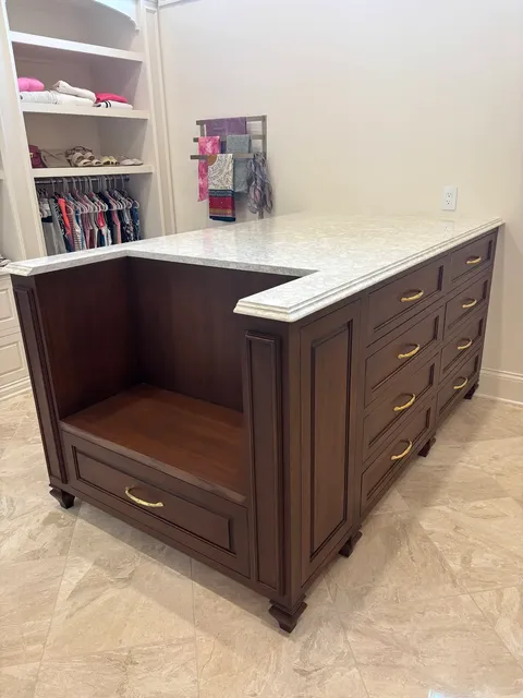 Dark walnut closet island with white marble countertop and open storage