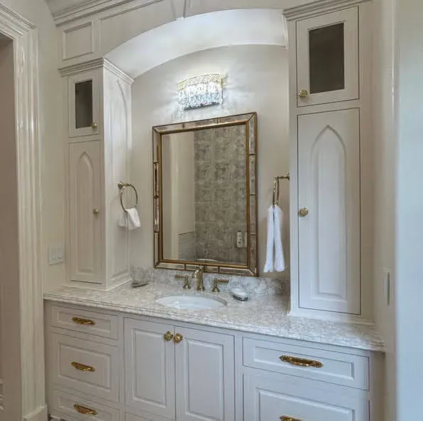 Curved bathroom vanity with light gray cabinetry and marble countertop