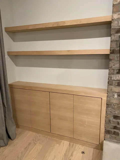 Light oak floating shelves with white backing and wood base cabinetry
