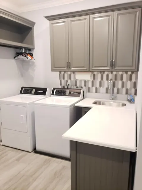 White laundry room with gray cabinets and geometric patterned backsplash