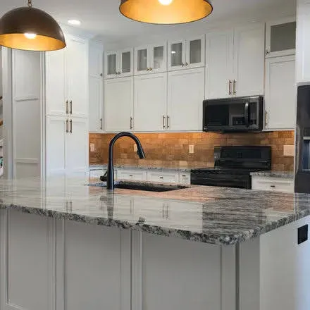 White kitchen with glass-front cabinetry, wooden backsplash and pendant lights