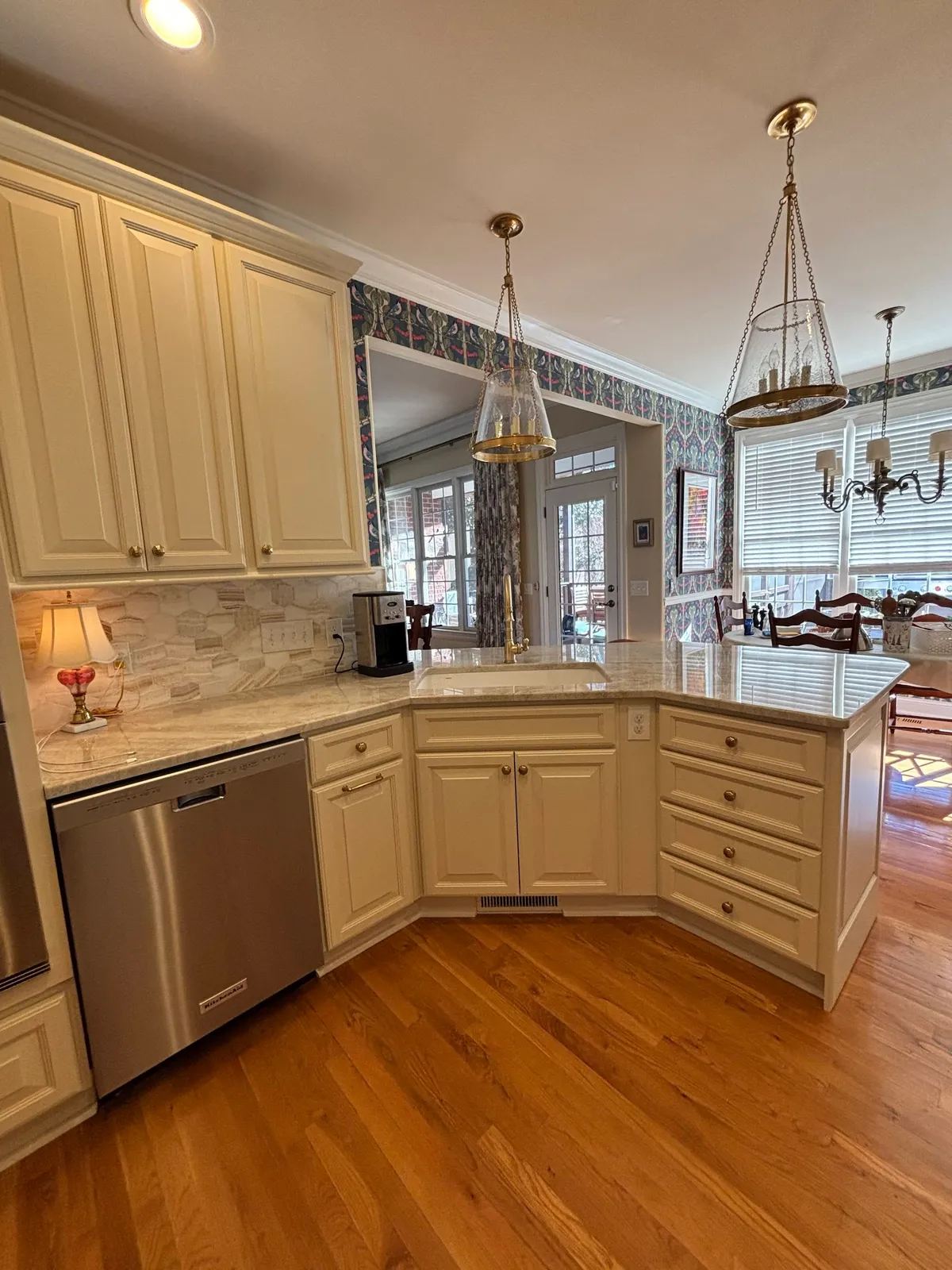 Cream kitchen with curved island, pale marble countertop and pendant lights