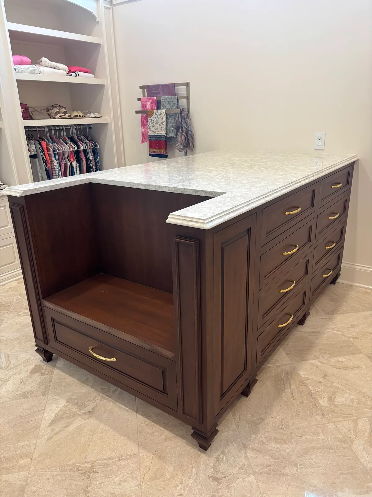 Dark walnut closet island with white marble countertop and open storage