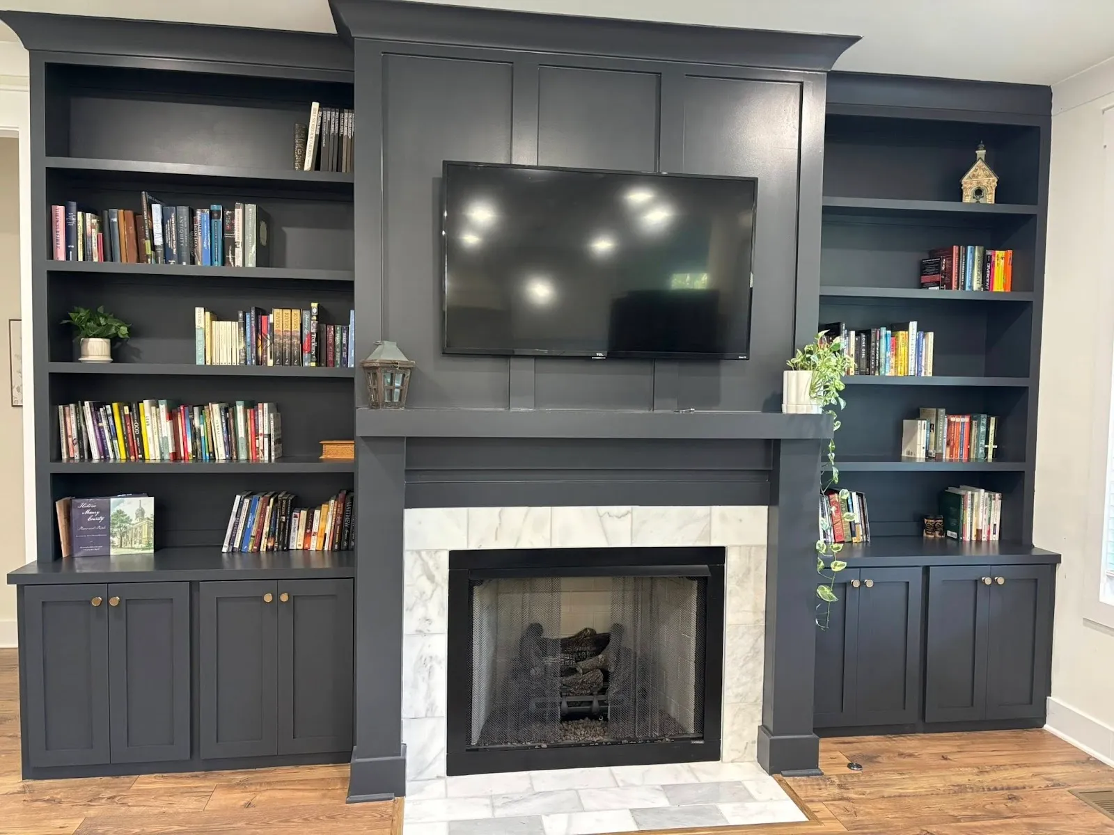 Dark slate fireplace surround with built-in shelving and TV mounting