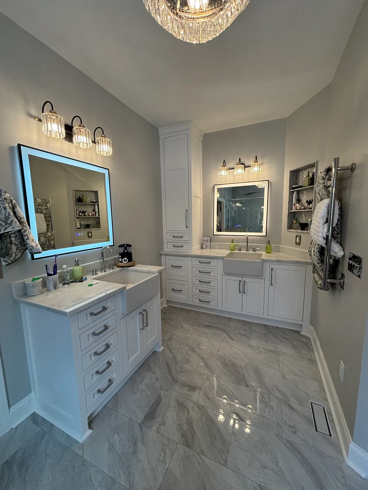 Master bathroom vanity with dual sinks, backlit mirror, and marble flooring