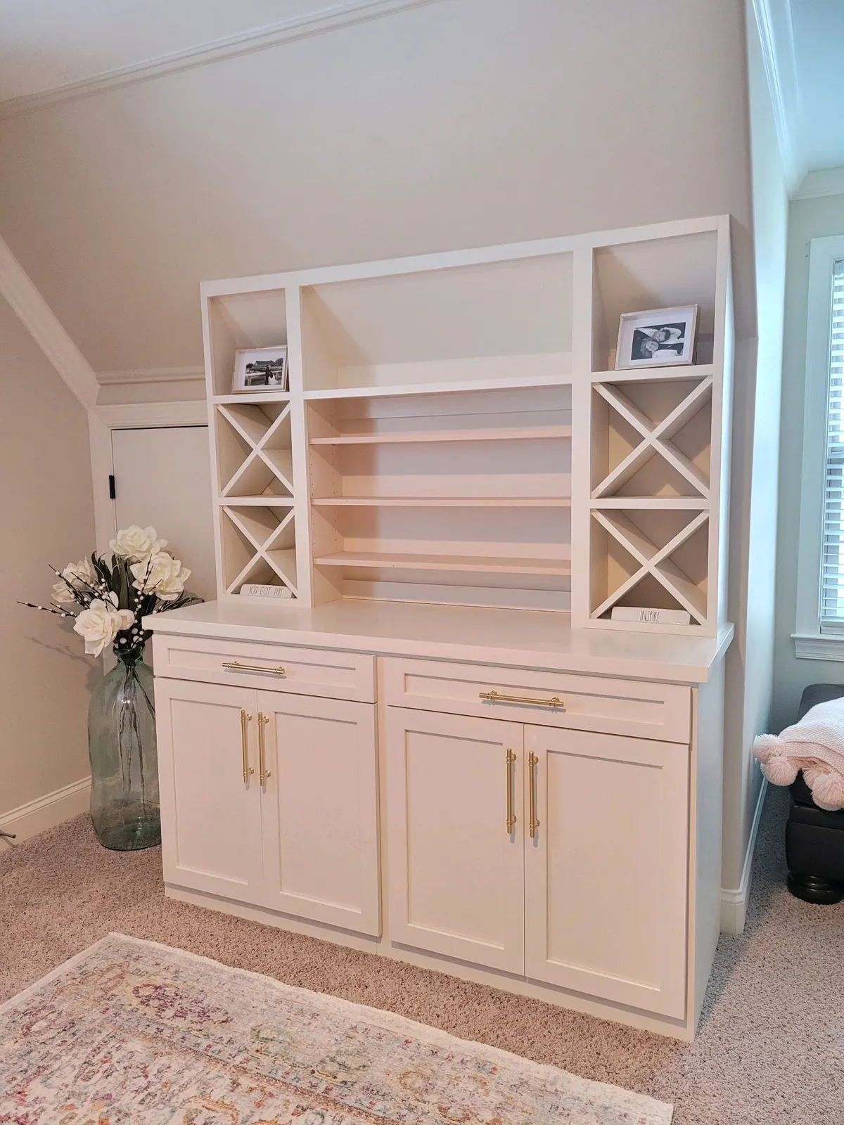 White built-in bookcase with X-pattern shelves and gold hardware