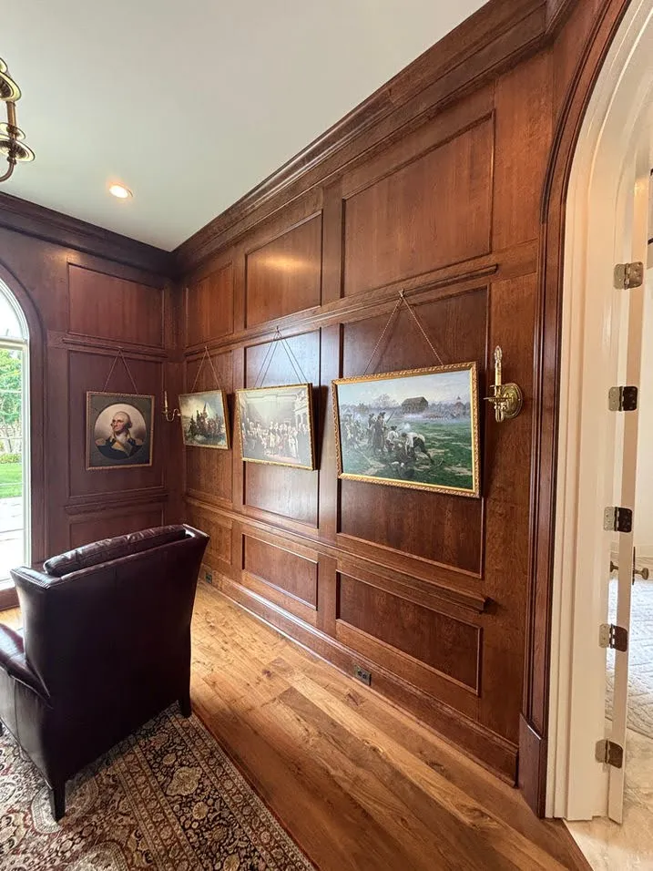 Rich walnut library with wood paneling and custom artwork display
