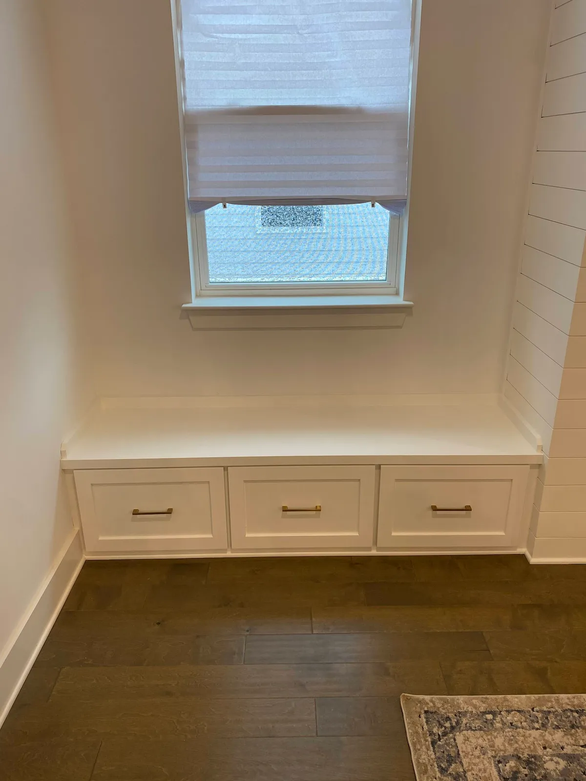 White window seat with three storage drawers and shiplap walls
