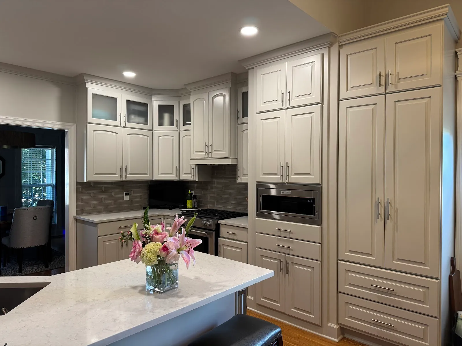 Beige kitchen with glass-door cabinets, marble island, stainless appliances