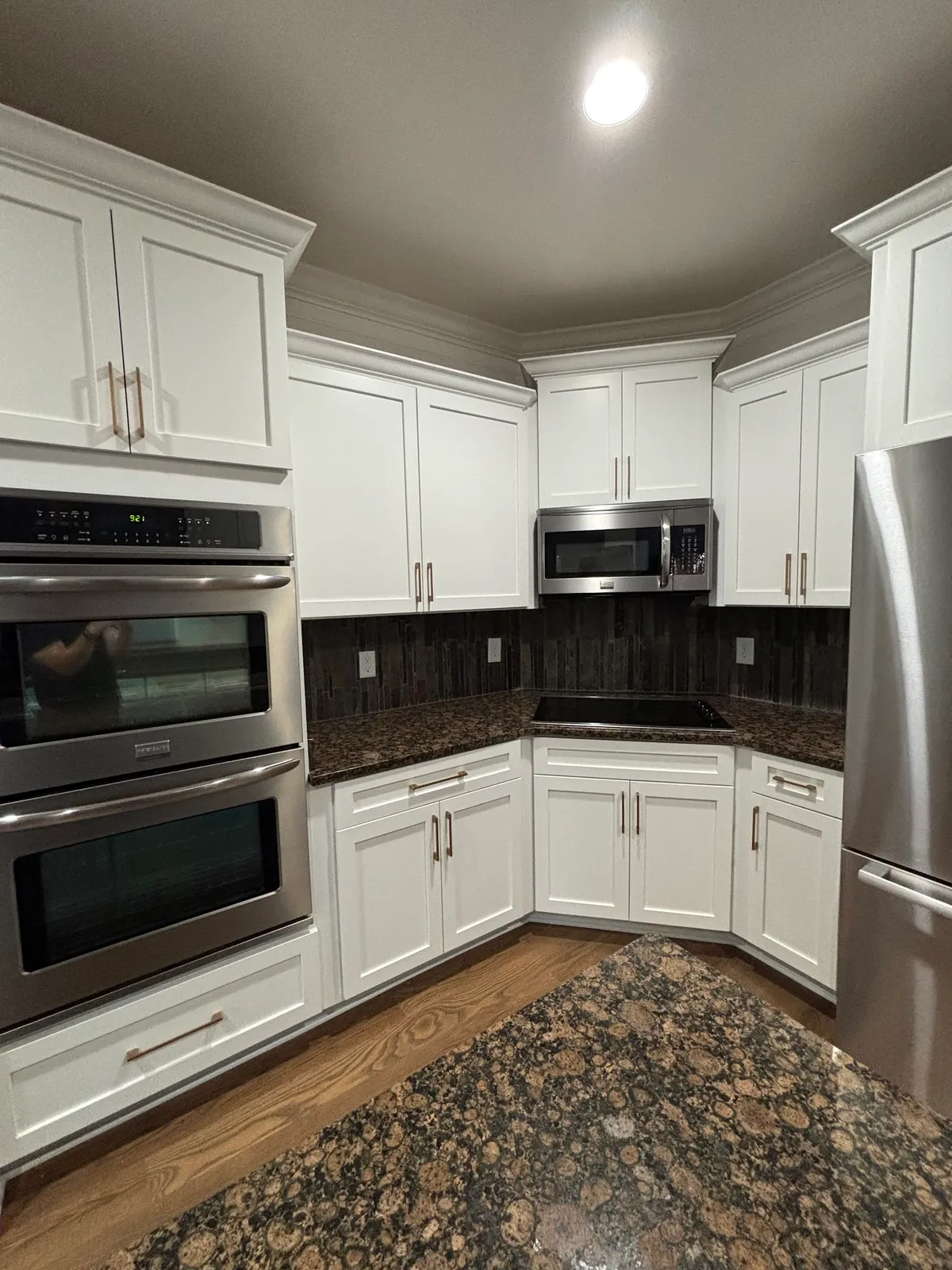 White shaker kitchen with dark backsplash and dual built-in wall ovens