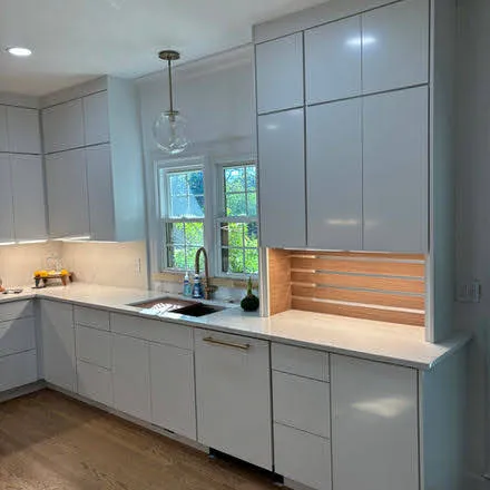 Contemporary white kitchen with glass-front upper cabinets and large windows