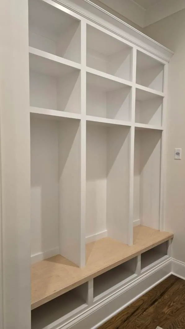 White built-in closet system with light wood shelving and shoe storage