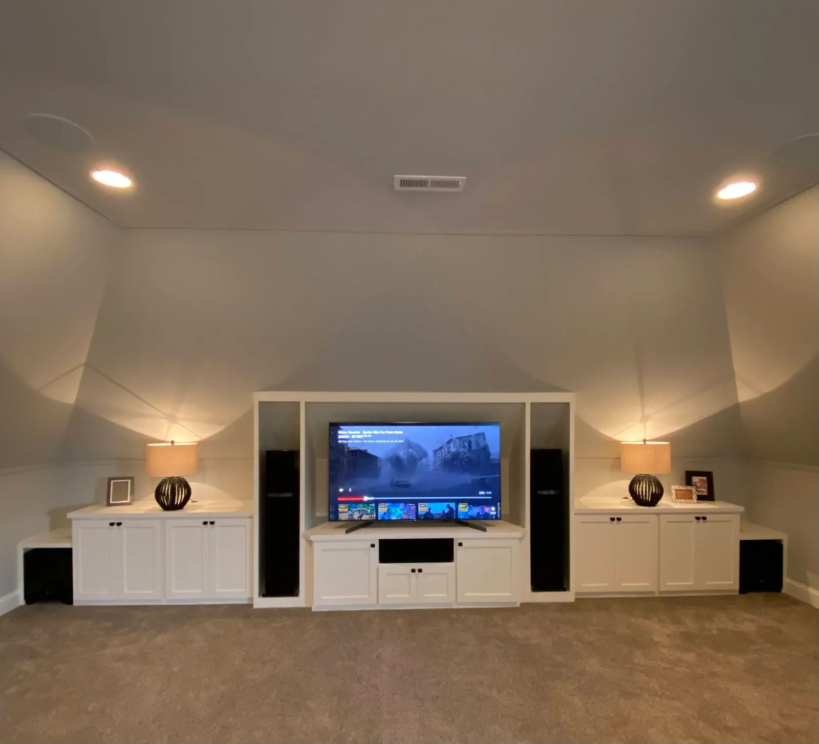 Entertainment center with white cabinetry and recessed lighting flanking TV