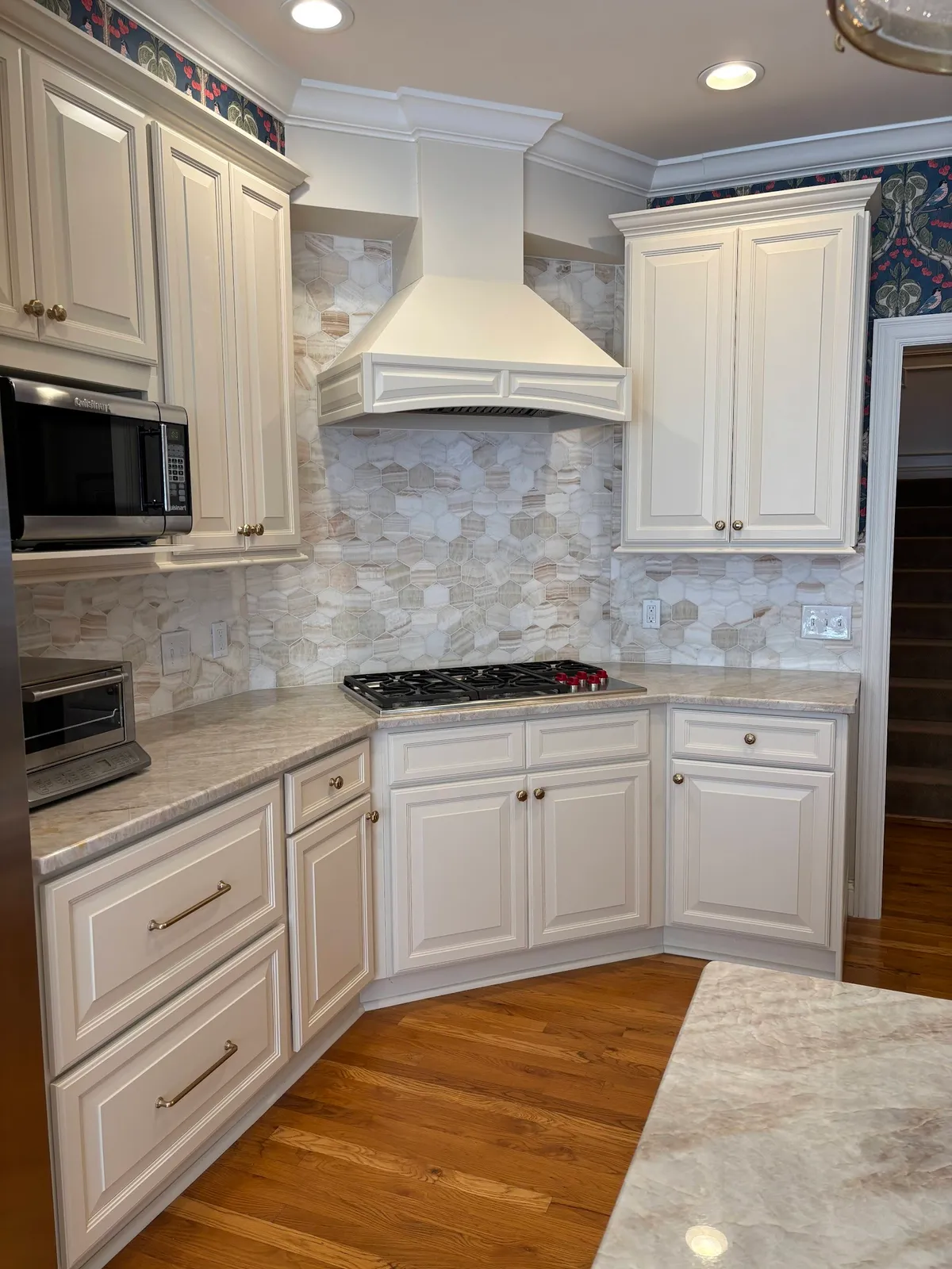 White kitchen with marble tile backsplash and cream range hood