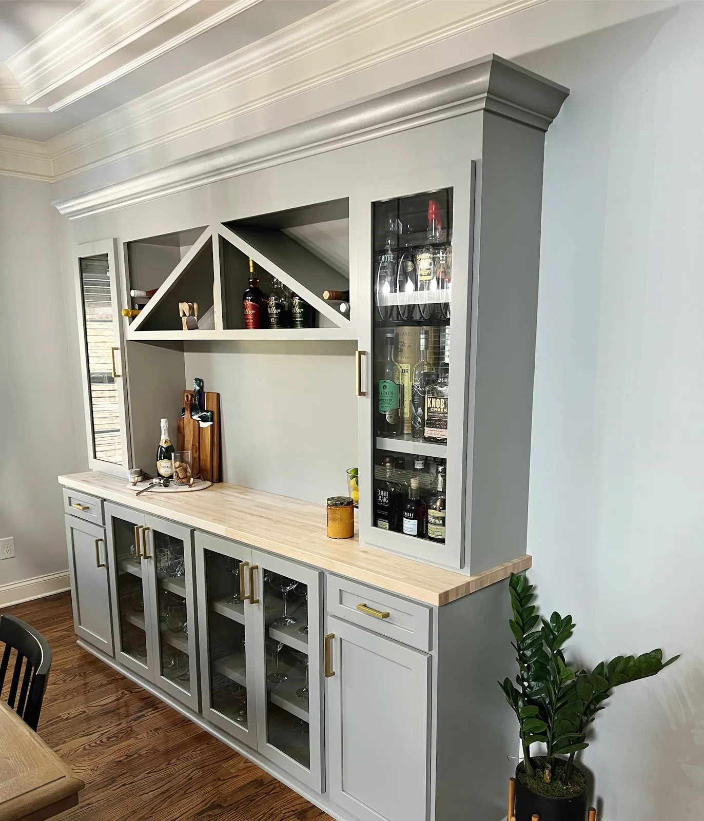 White bar cabinet with wood countertop and glass-front beverage cooler