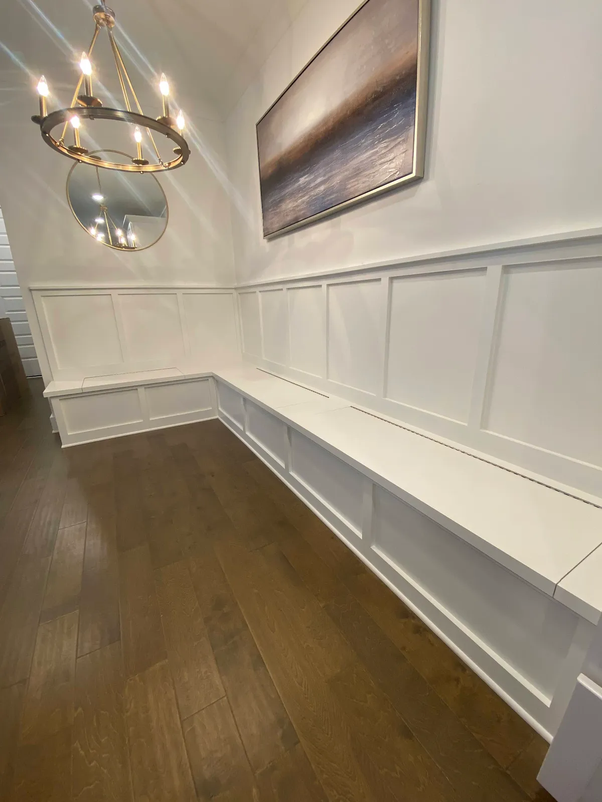 White wainscoting with banquette seating and brass chandelier lighting