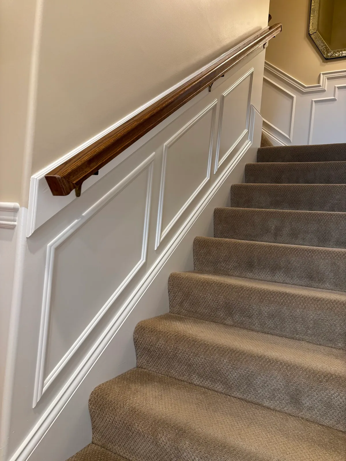 Staircase with white paneled wainscoting and dark walnut handrail