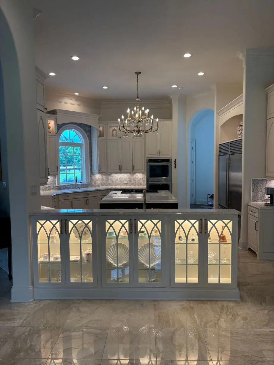 White kitchen with geometric glass-front lower cabinetry and island