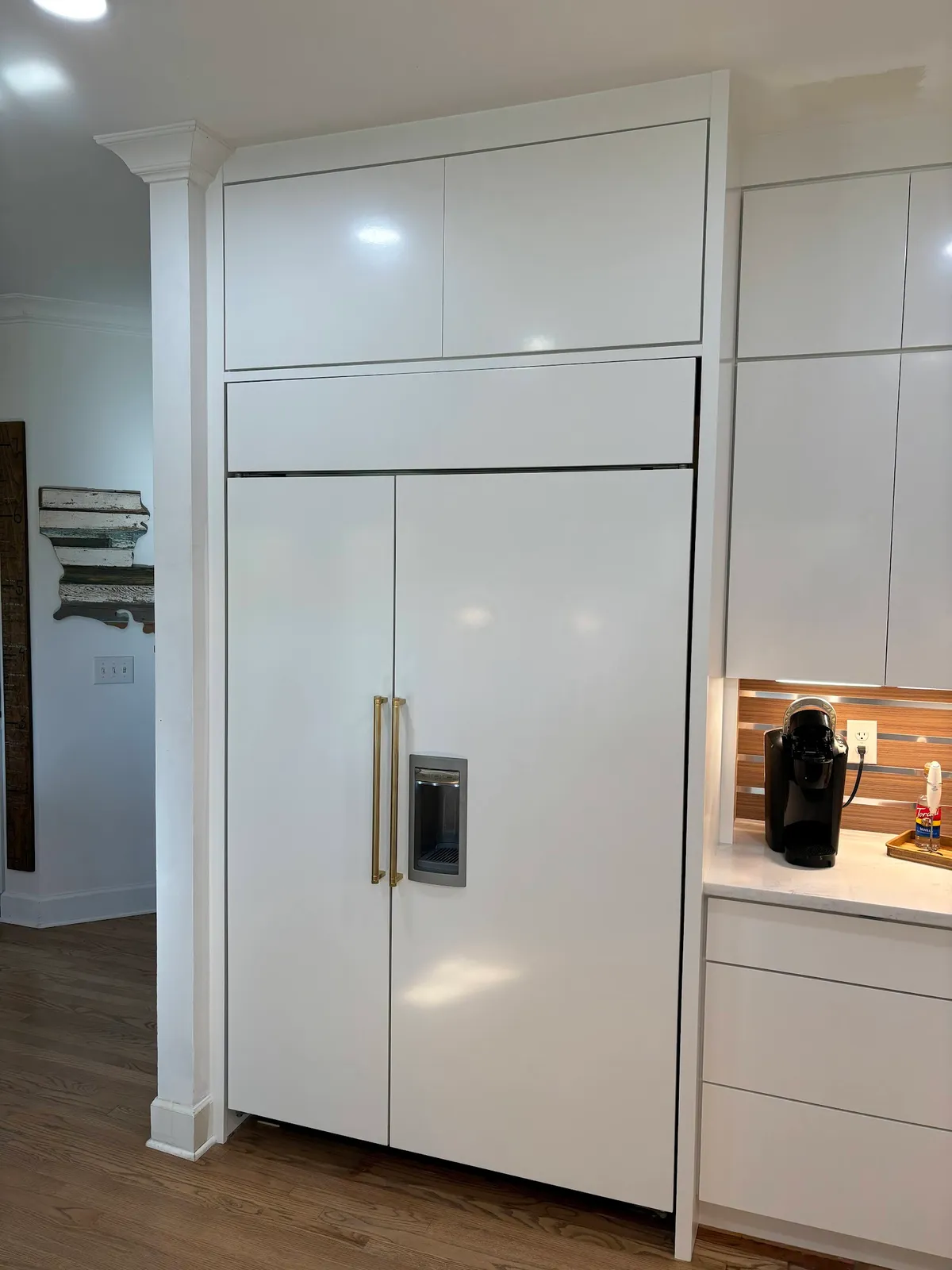 White refrigerator with glass door panels built into white cabinetry