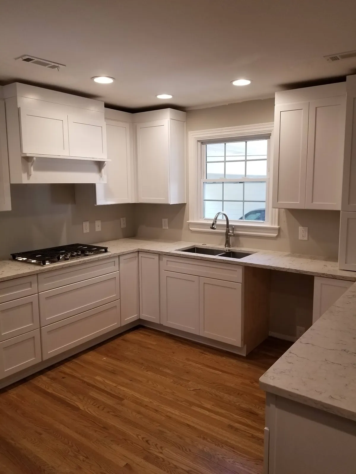 White shaker kitchen with marble counters, gas cooktop, and corner island