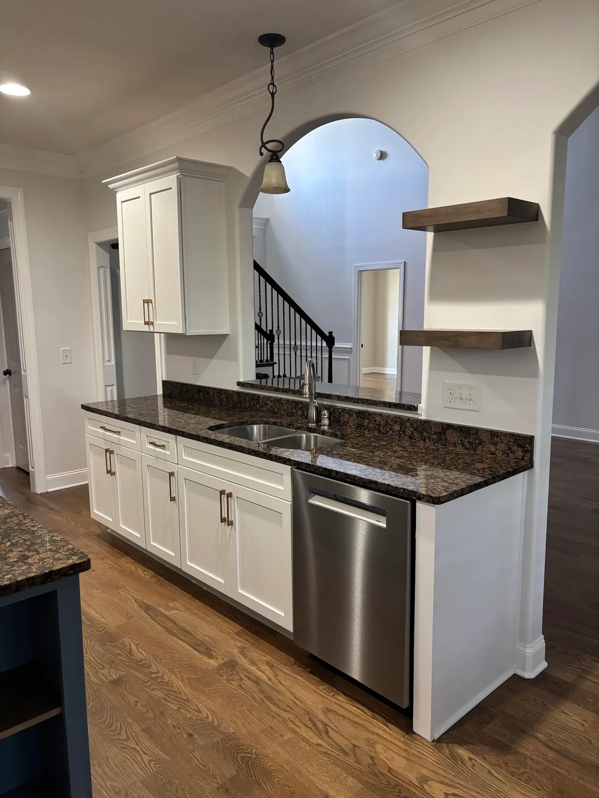 White kitchen with black granite island and floating wood shelves