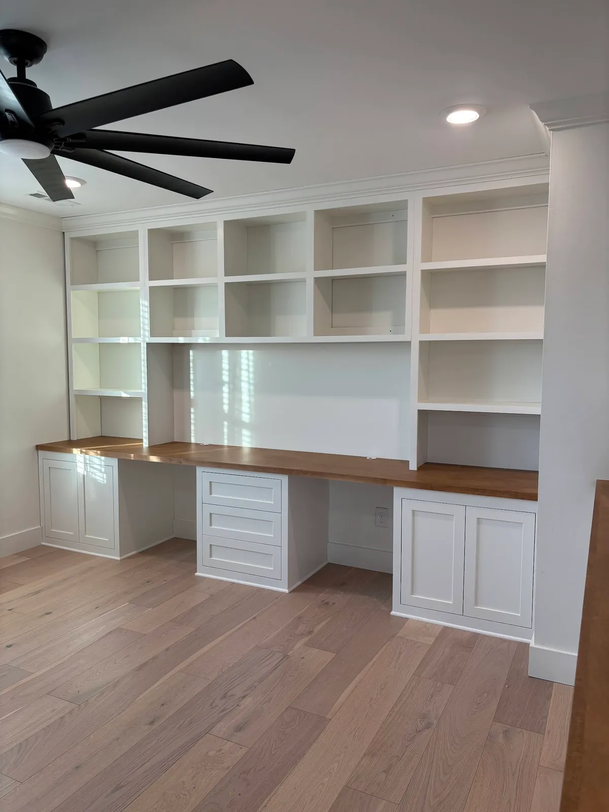 White built-in desk with wood countertop, glass shelves and grid pattern