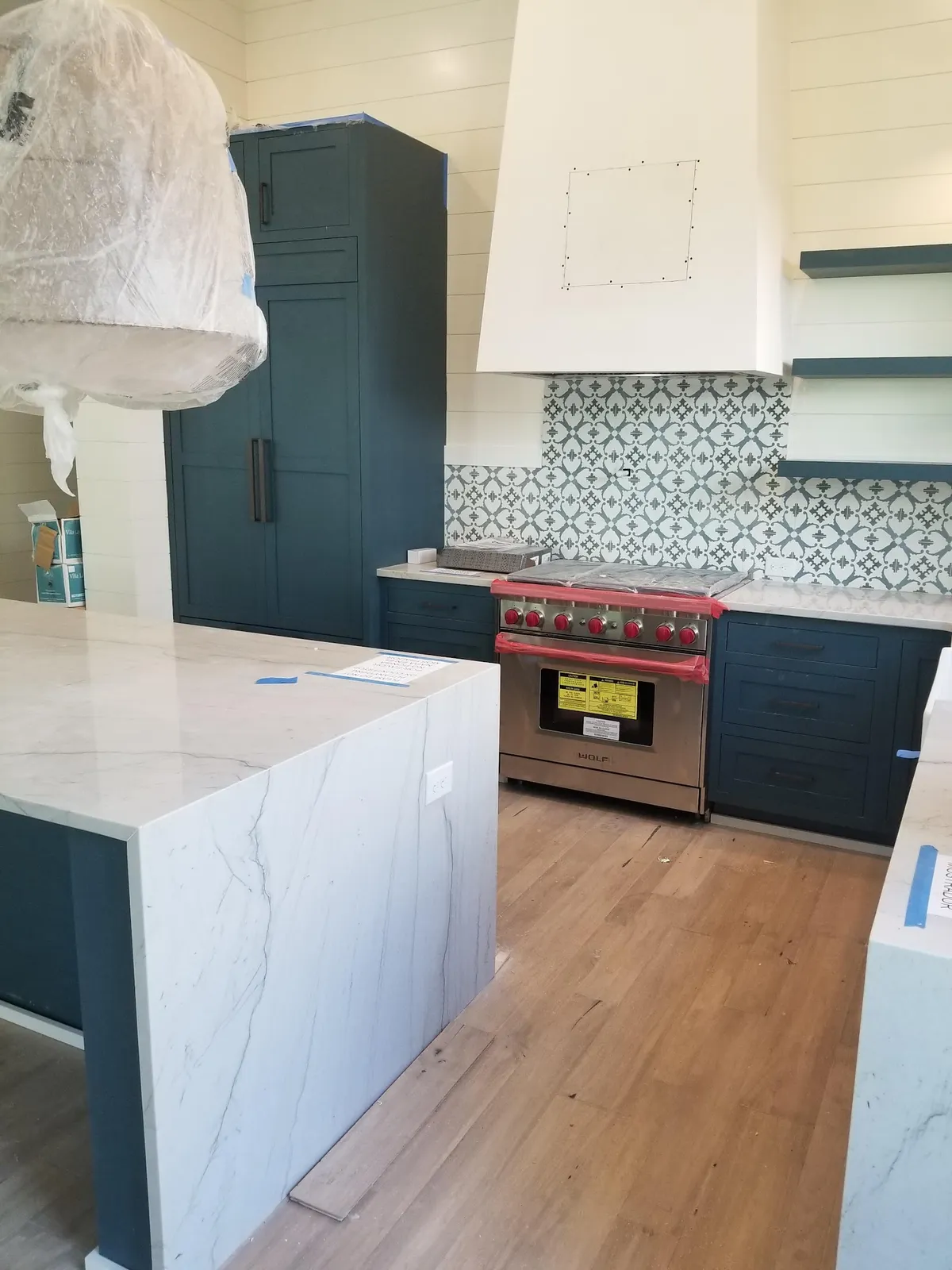 Navy blue kitchen with white island and geometric tile backsplash
