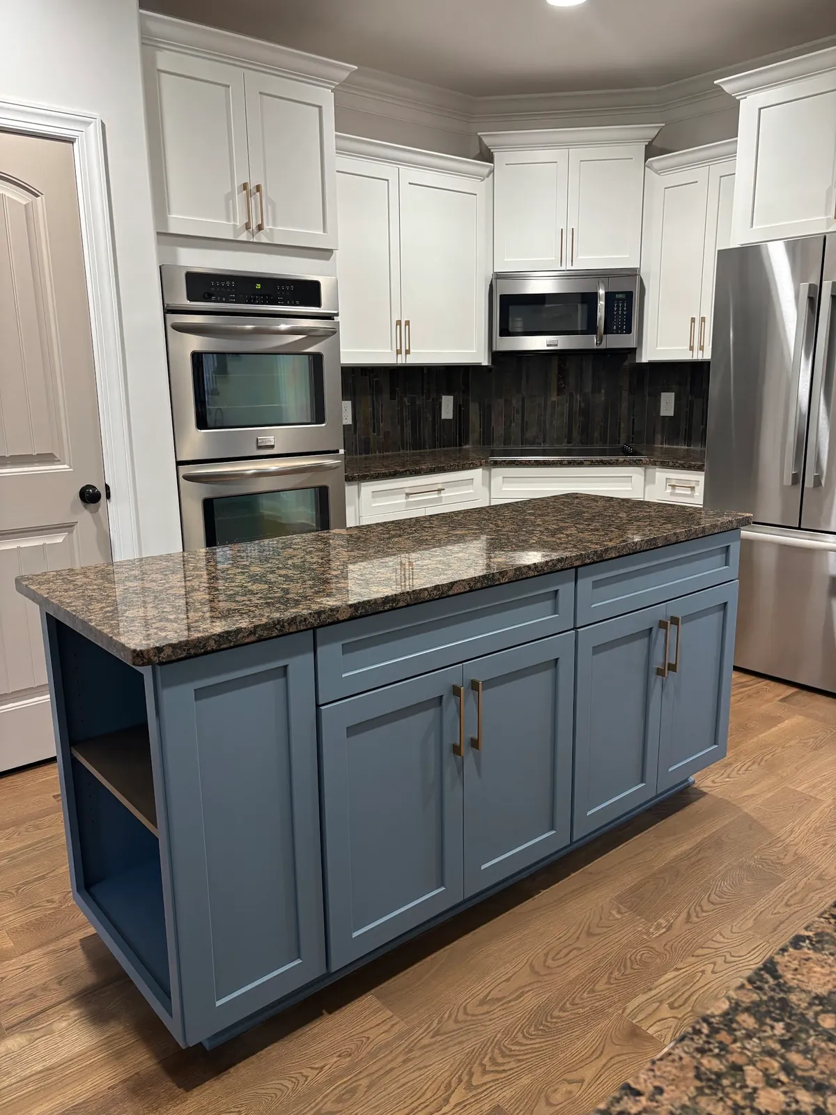 White kitchen with blue island, double wall ovens and granite countertop