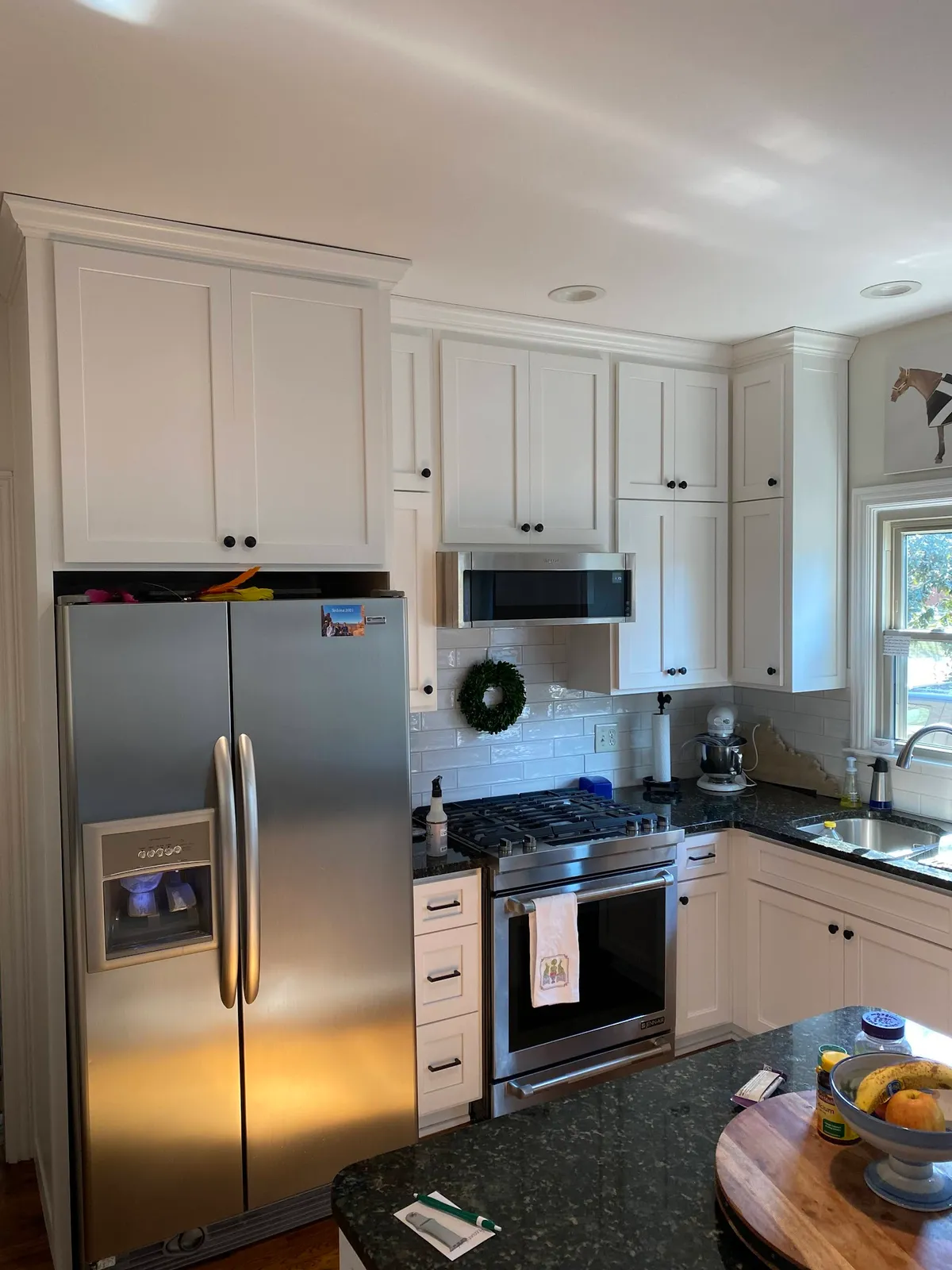 White kitchen with stainless appliances, subway backsplash and dark counters