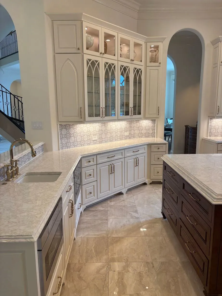 White kitchen with glass-front doors, granite counters and arched opening