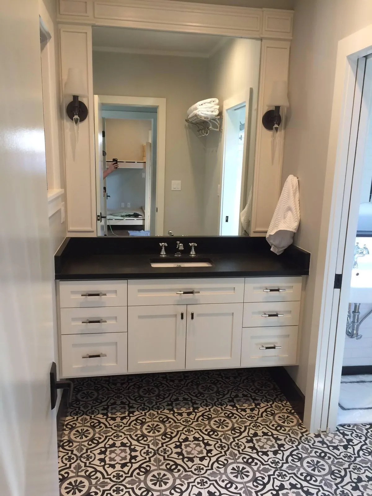 Cream bathroom vanity with black countertop, mirror cabinetry and patterned tile