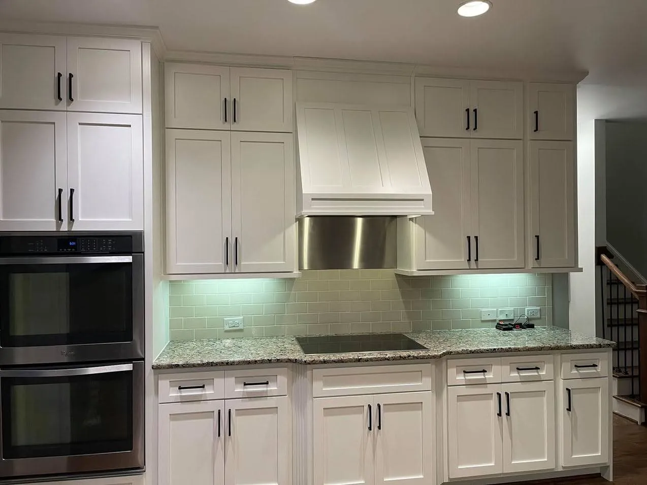 White shaker kitchen with granite counters, subway backsplash and steel hood