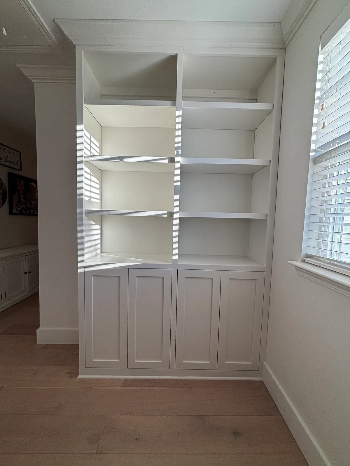 White built-in shelving with glass-front cabinets and open window shelves