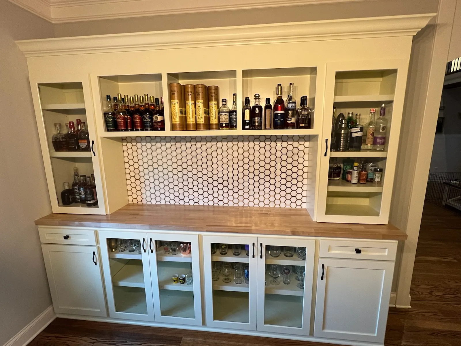 Home bar with white cabinetry, hexagon tile backsplash and walnut counters