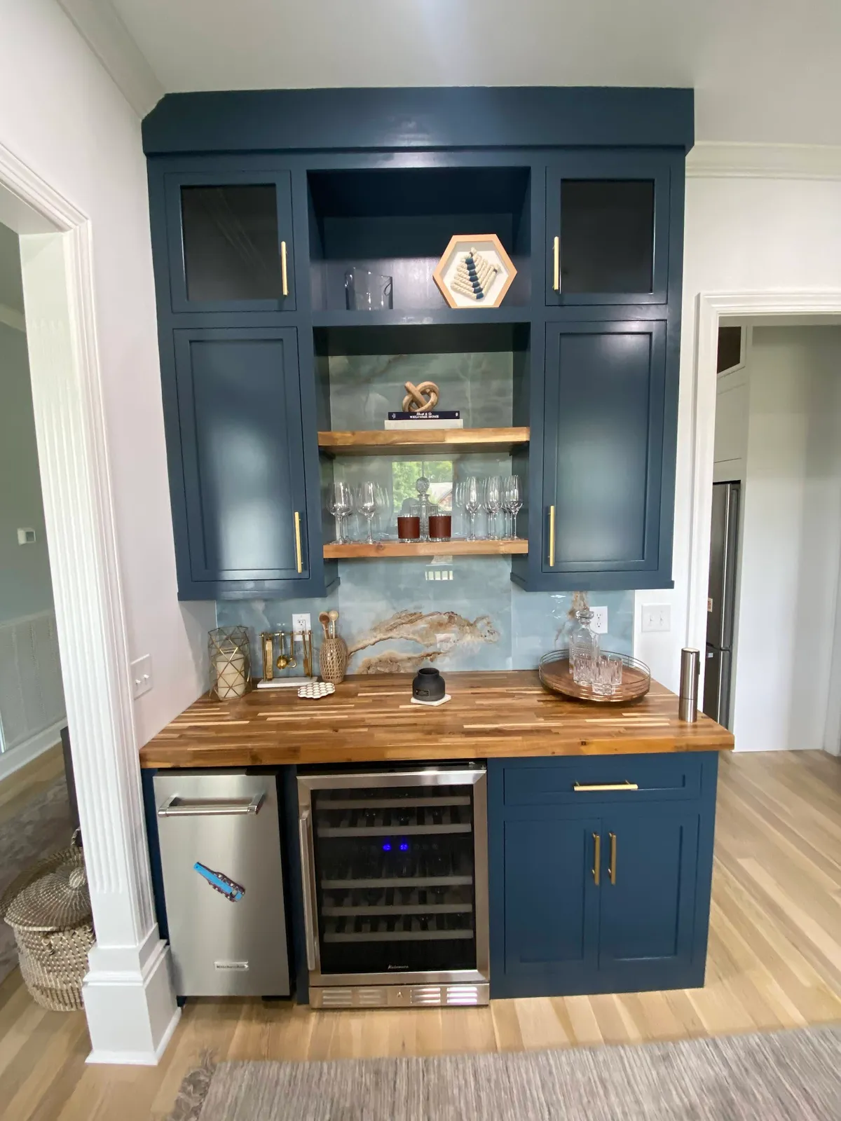 Navy blue home bar with wood shelves, wine cooler and glass-front cabinets