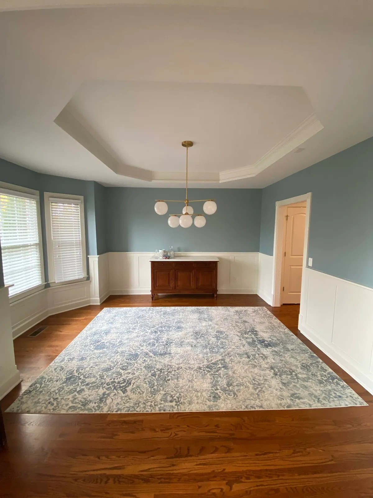 Formal dining room with wainscoting, tray ceiling detail and walnut sideboard
