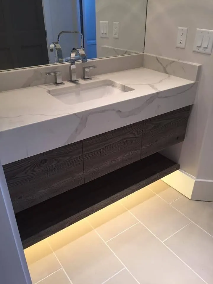 Bathroom vanity with dark wood base, white quartz countertop and bronze hardware