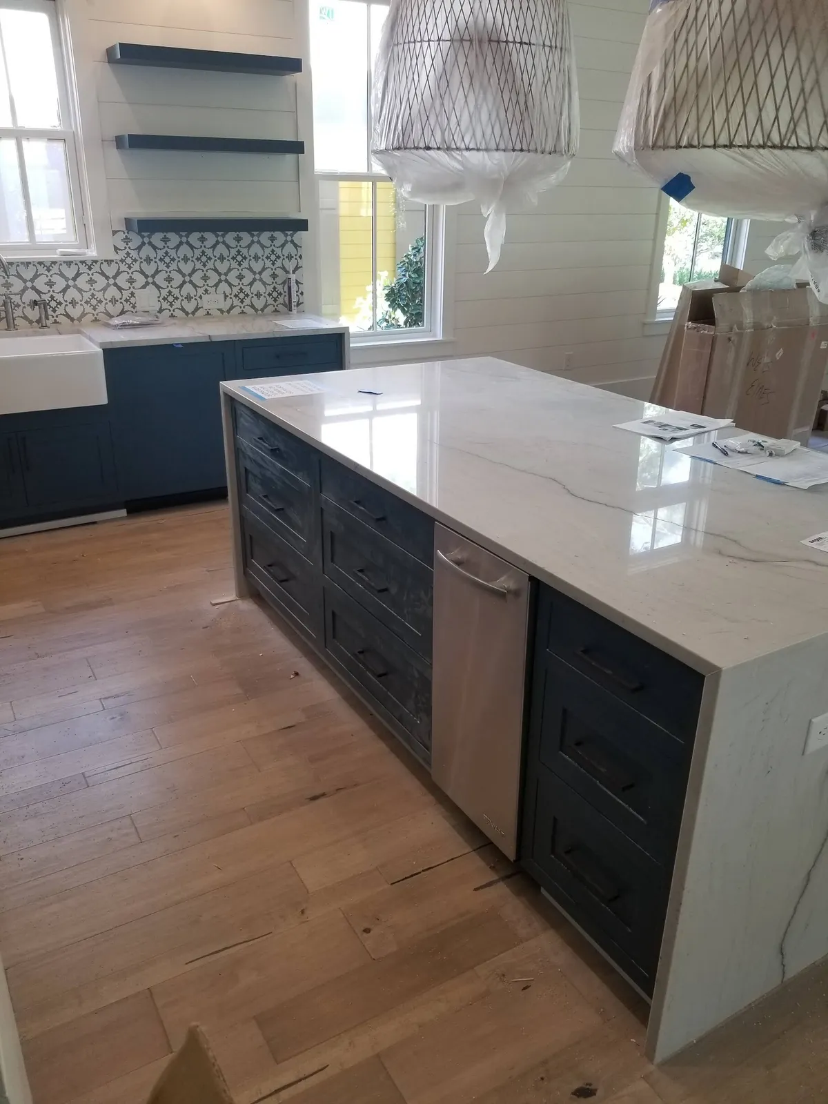 Navy kitchen with white quartz island, hexagon backsplash and pendant lighting
