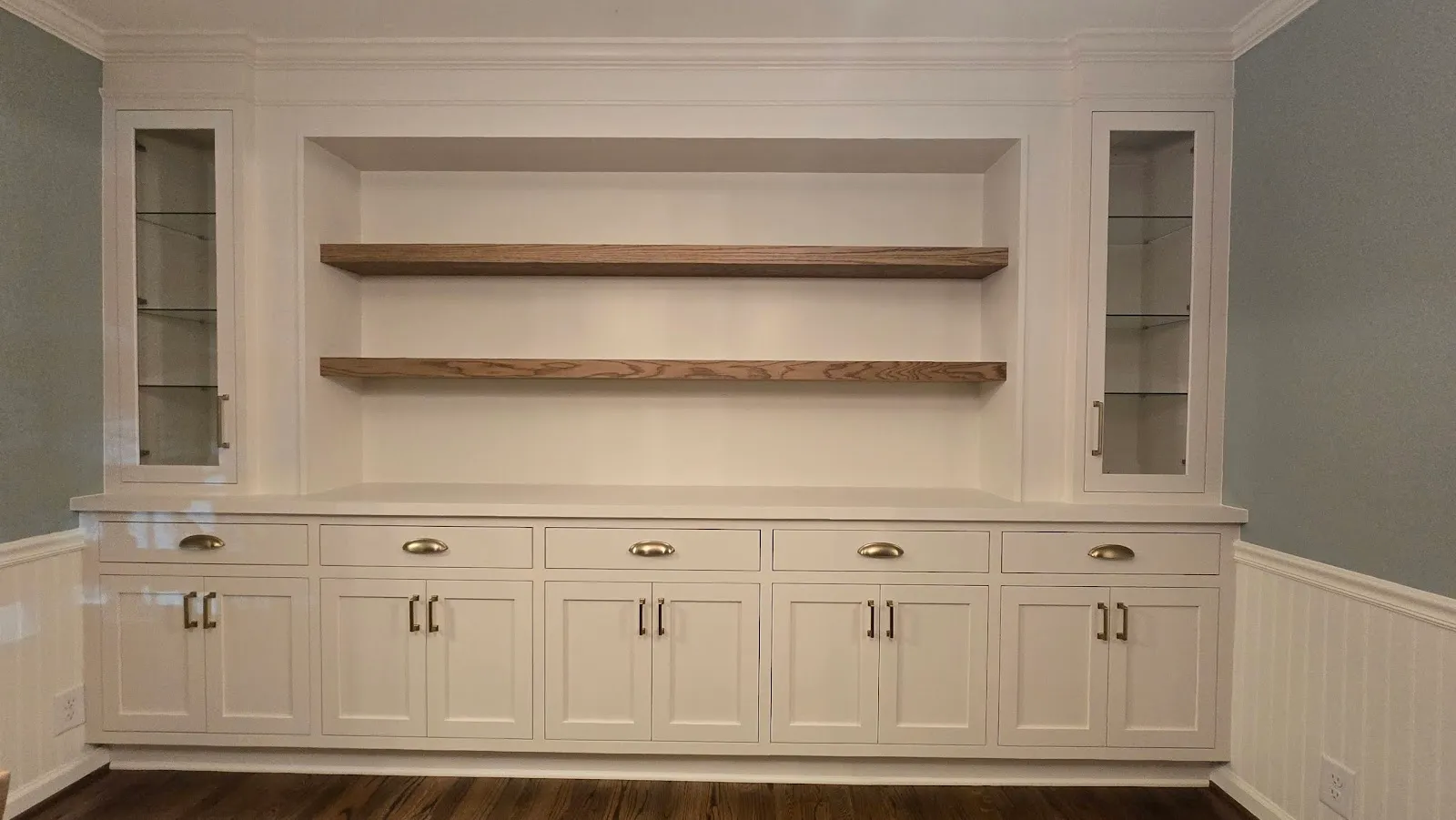 White built-in shelving with walnut shelves and multiple storage cabinets