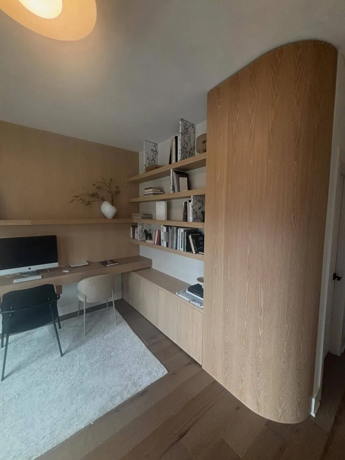 White custom workspace with walnut desk, built-in shelving and curved design