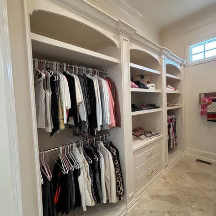 White walk-in closet with double rods, shelving and organized cubbies