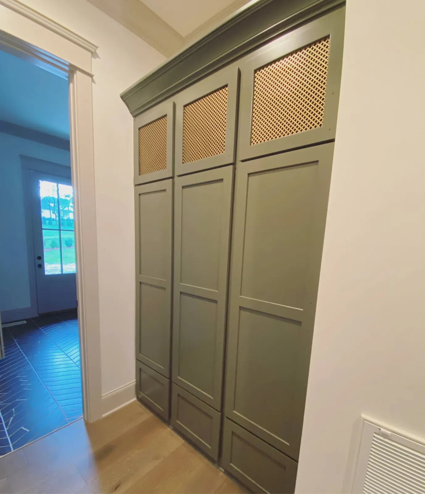 Sage green mudroom lockers with perforated mesh glass-front doors