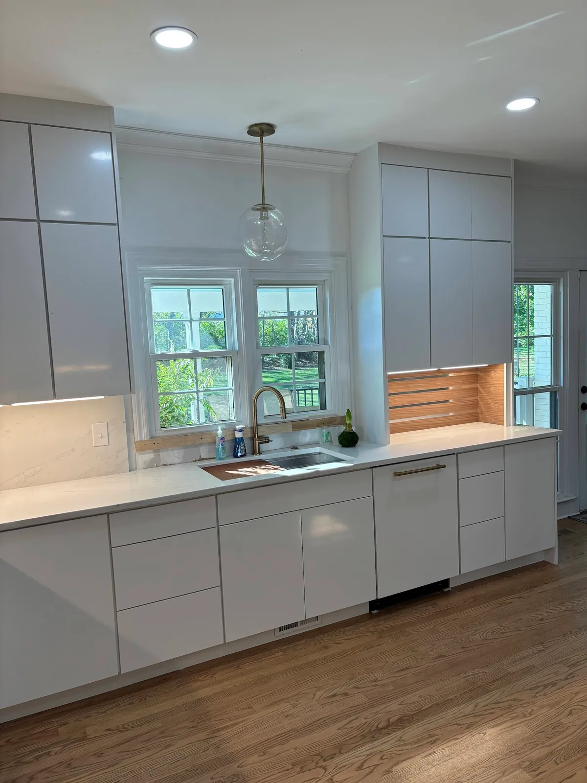 Modern white kitchen island with waterfall countertop and wood backsplash