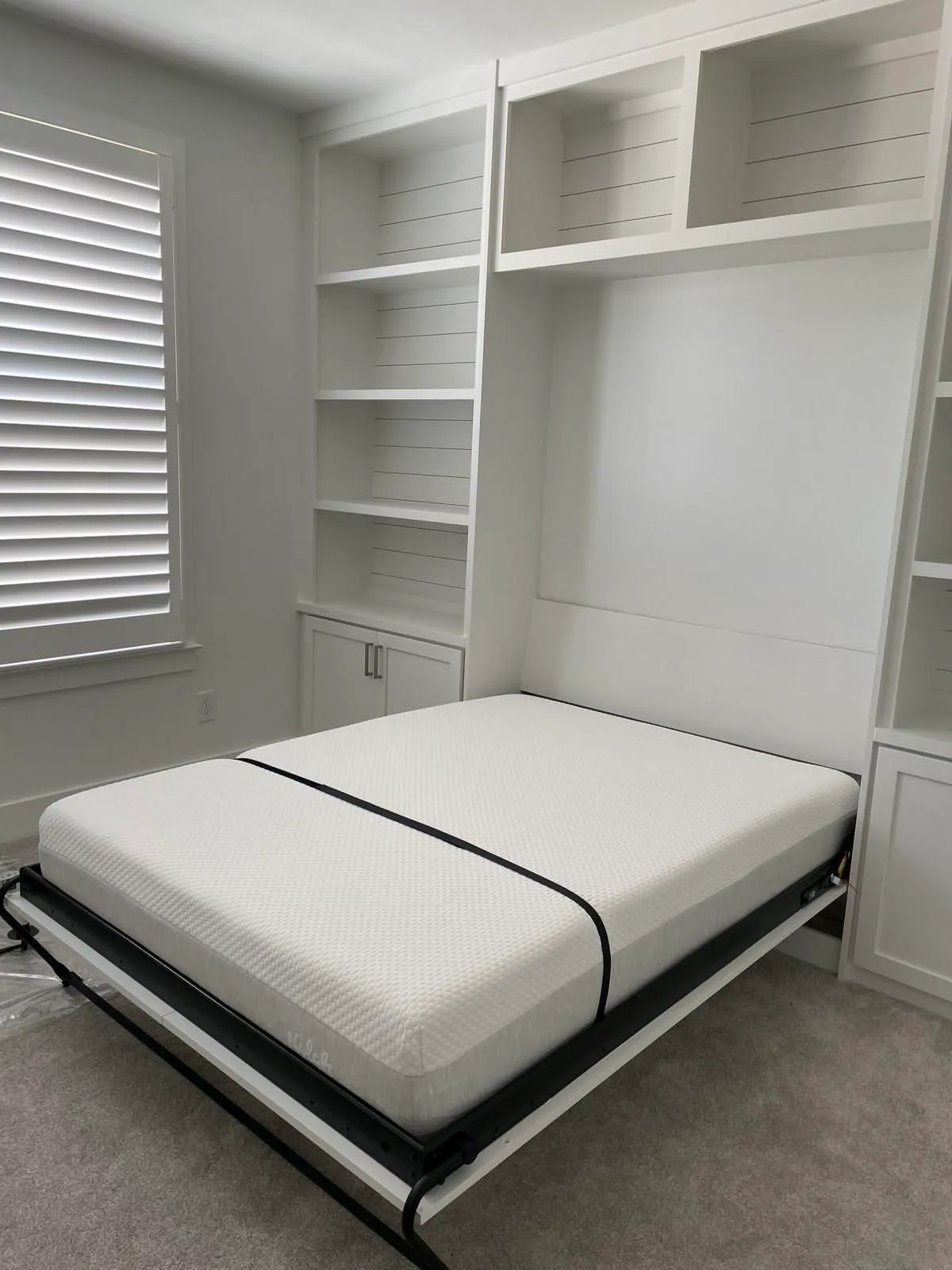 White murphy bed cabinetry with extensive shelving and shiplap backing