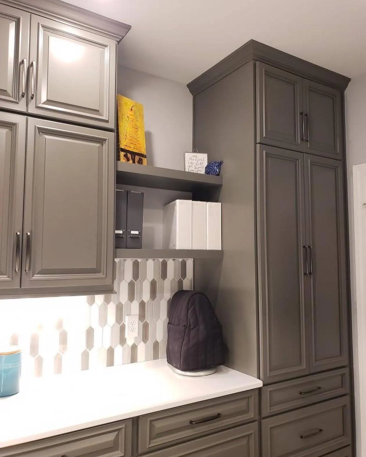 Taupe mudroom cabinetry with hexagon tile backsplash and wine fridge