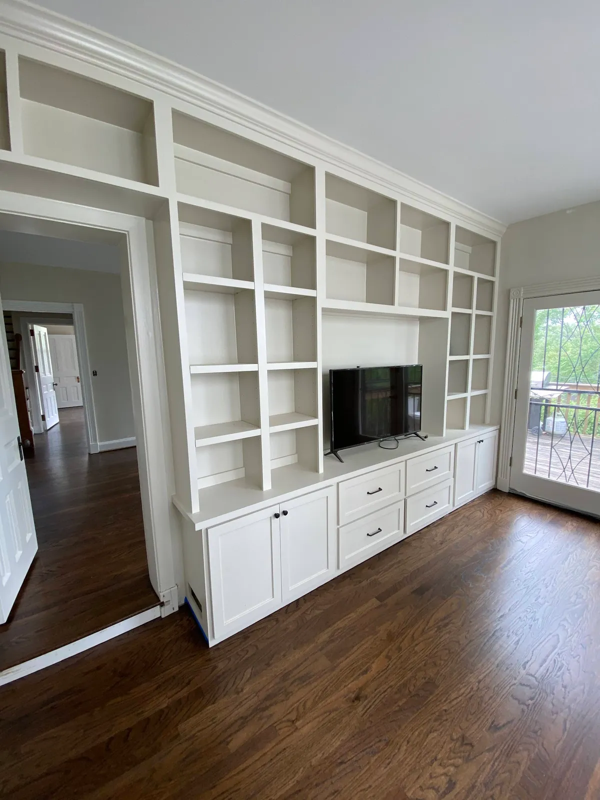 White wall-to-wall built-in shelving with lower storage cabinets and cubbies