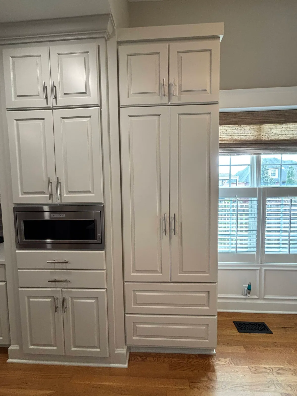 Cream kitchen pantry with microwave alcove and tall glass-front cabinetry