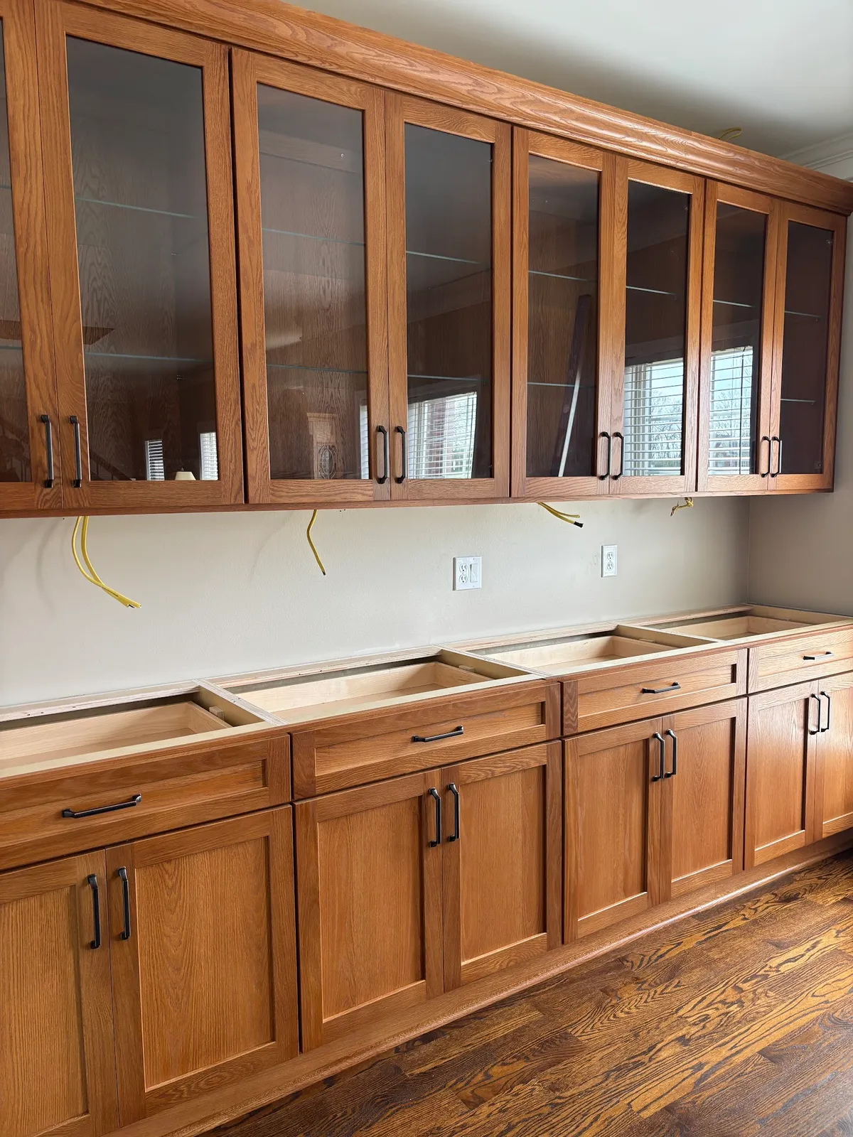 Stained oak cabinetry with glass-front uppers and hardware pulls detail